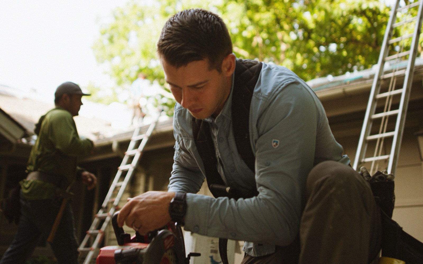 Home-service contractor using a saw on a job site with his crew